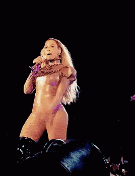 a woman in a bodysuit is holding a microphone on stage