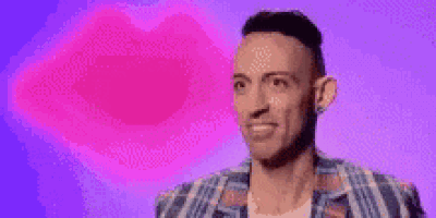 a man in a plaid shirt is standing in front of a purple background with a pink heart in the background .