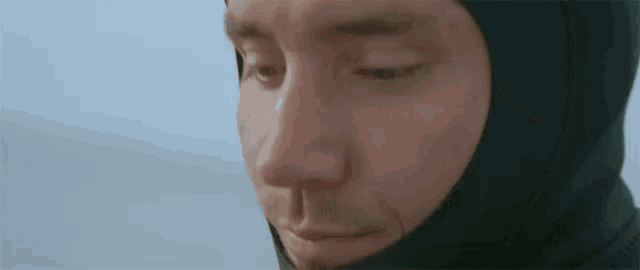 a close up of a man 's face wearing a hooded wet suit .