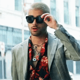 a man wearing a suit and sunglasses is adjusting his glasses .