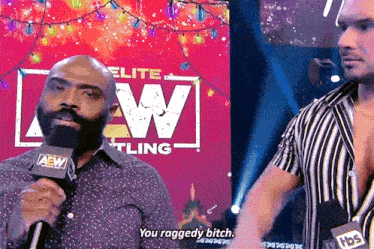 a man with a microphone in front of a sign that says elite wrestling
