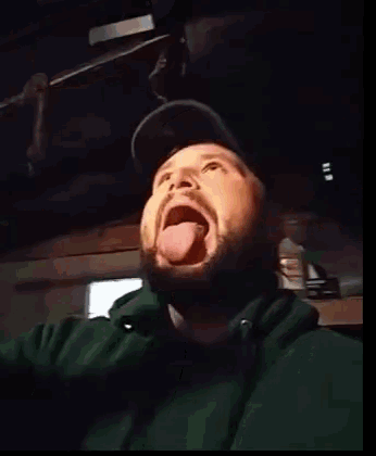 a man with a beard is sticking his tongue out in a dark room .