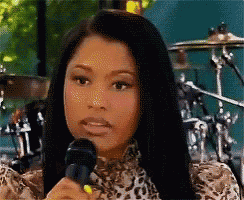a woman in a leopard print shirt is holding a microphone and making a funny face .