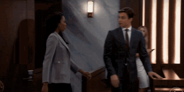 a woman in a purple jacket and a man in a suit shake hands