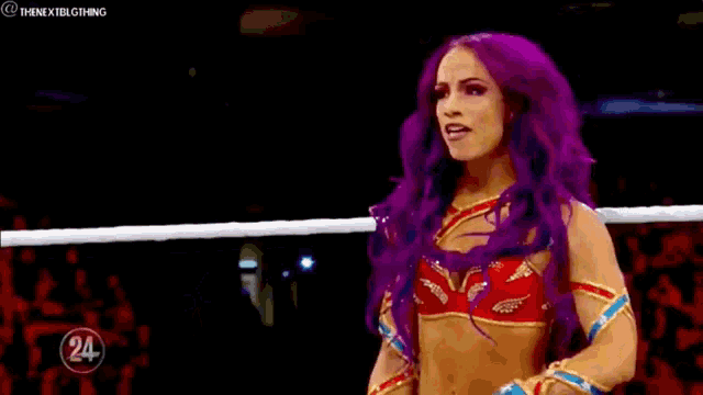 a female wrestler with purple hair is standing in a wrestling ring .