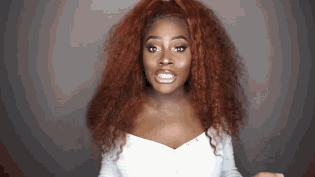 a woman with red hair is wearing a white shirt and making a funny face