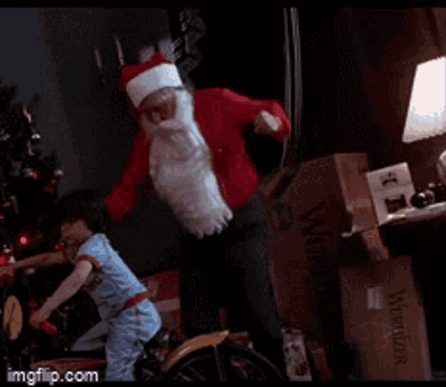 a man in a santa suit is standing next to a child on a bike