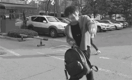 a black and white photo of a person walking down a street with a backpack .
