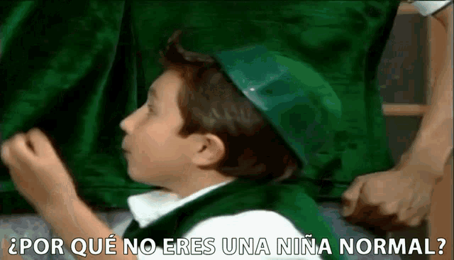 a young boy wearing a green hat and a green vest is asking a question .