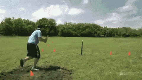 a man in a blue shirt and black shorts is swinging a bat