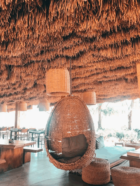 a wicker chair under a thatched roof in a restaurant