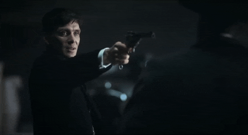 a man in a suit is pointing a gun at another man with the words reason two below him