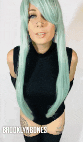 a woman with long green hair is wearing a black top and black thigh high socks