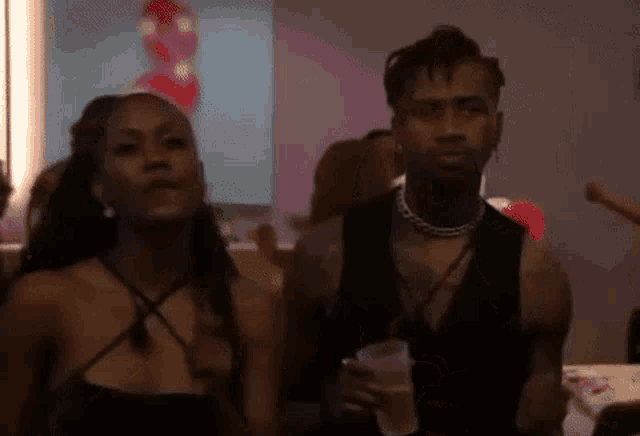 a man and a woman are standing next to each other at a party in a room .