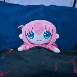 a stuffed animal with pink hair and blue eyes is sitting on a bed .