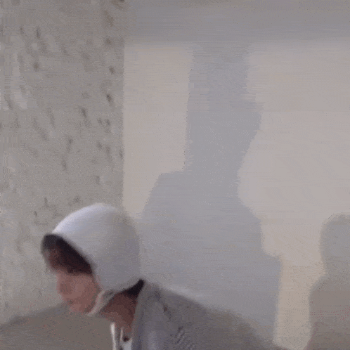 a man wearing a sweater and a hooded hat is sitting on the floor in a room .
