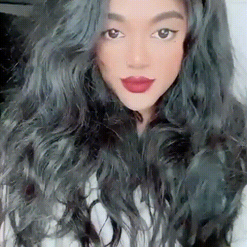 a close up of a woman 's face with long green hair and red lips .
