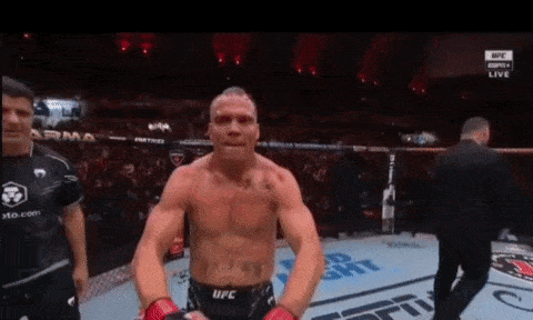 a man in a ufc uniform is standing in a ring with a referee .