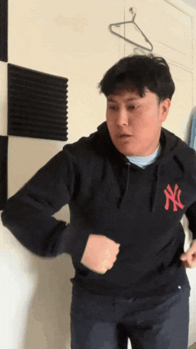 a man wearing a black ny yankees sweatshirt