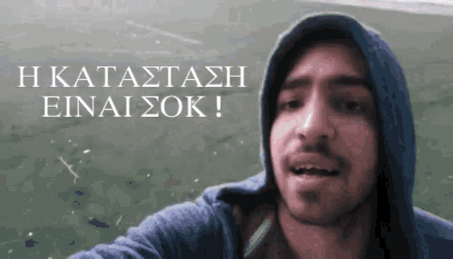 a man wearing a blue hoodie is talking in greek
