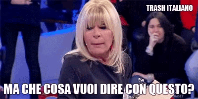 a woman with blonde hair is sitting in front of a crowd and says trash italiano