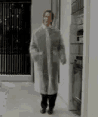 a woman in a white coat walking down a hallway