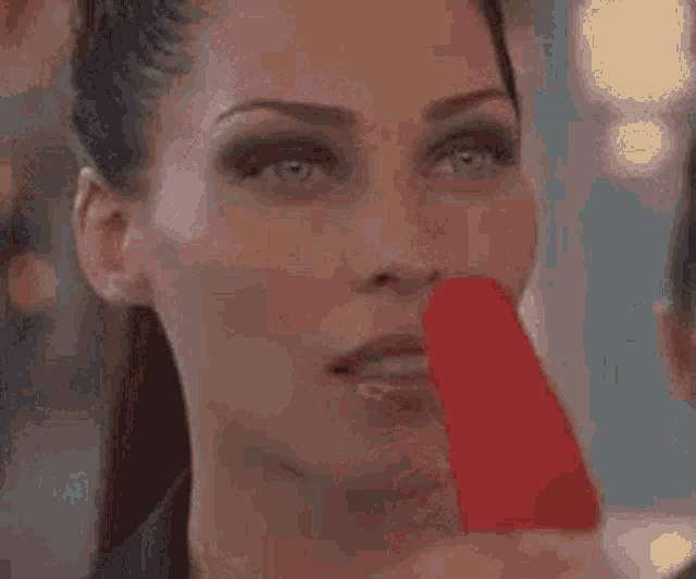 a close up of a woman covering her mouth with her finger .
