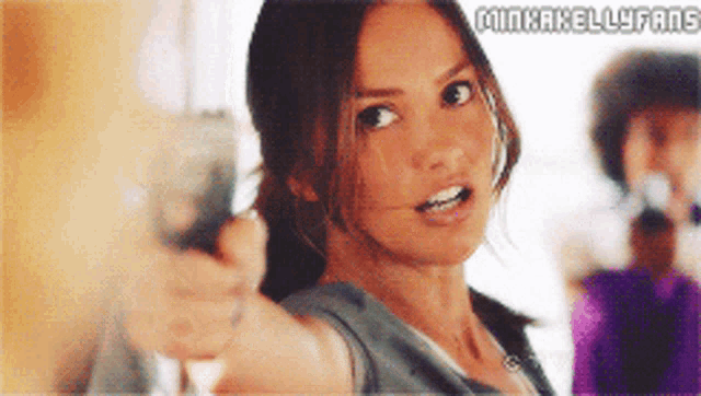a woman is pointing a gun at the camera with the words minhakellyfans on the bottom
