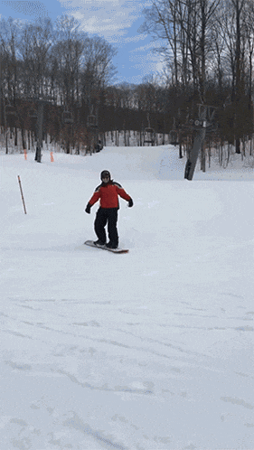 a person in a red jacket is snowboarding down a snow covered hill