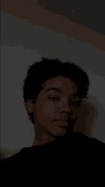 a young man with curly hair is making a face in the dark
