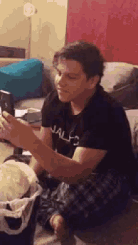 a man is sitting on a couch looking at his phone .