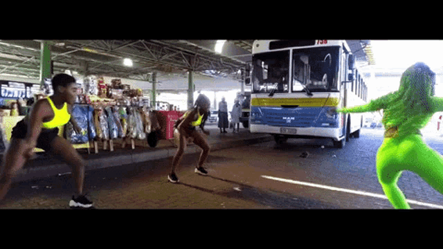 two women in neon green pants are dancing in front of a bus that says man