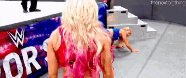 a woman in a pink top is standing next to a woman in a blue top on a stage .