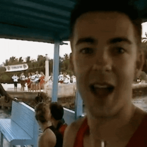 a man in a red tank top is standing in front of a sign that says welcome