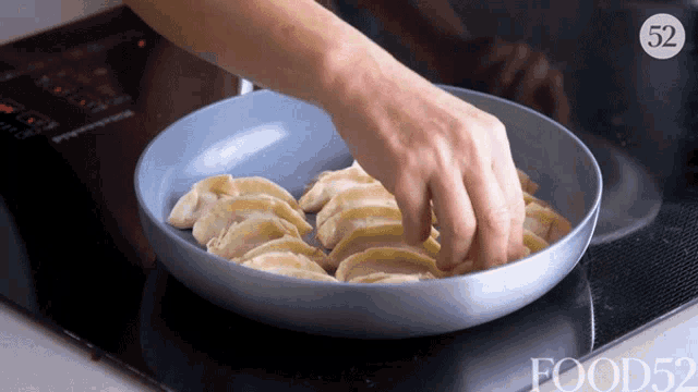 a person is cooking dumplings in a frying pan and the number 52 is on the stove
