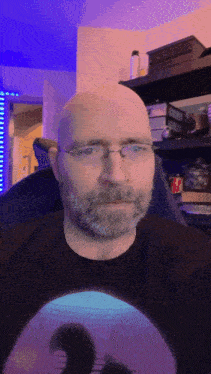 a man with glasses and a beard wears a black shirt