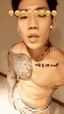a shirtless man with tattoos on his chest and arms is taking a selfie in a bathroom .