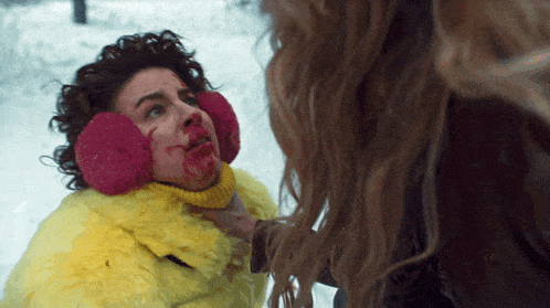 a woman wearing pink ear muffs and a yellow fur coat is being held by another woman