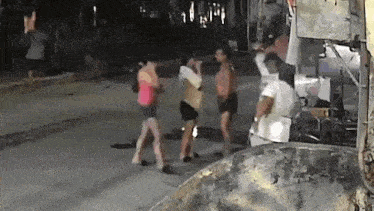 a group of people are standing on a sidewalk in front of a building at night .