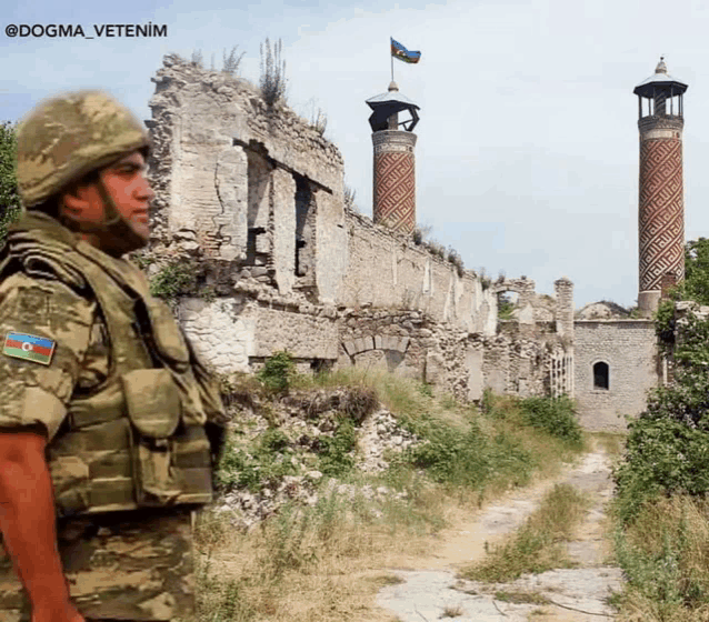 a man in a military uniform stands in front of a destroyed building