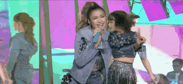 a woman singing into a microphone while another woman stands behind her