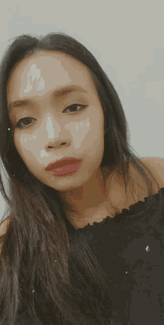 a woman wearing a black off the shoulder top has the words love and you written on her face