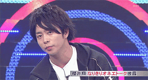 a man in a black jacket stands in front of a colorful background with chinese writing on it