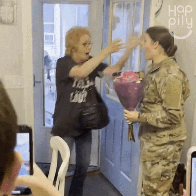 a woman holding a bouquet of flowers is being greeted by a soldier