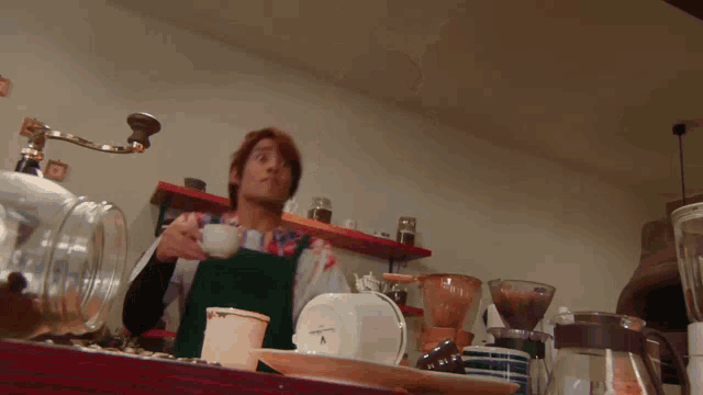 a man in an apron holds a cup of coffee