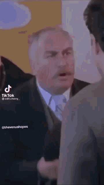 a man in a suit and tie is talking to two other men .