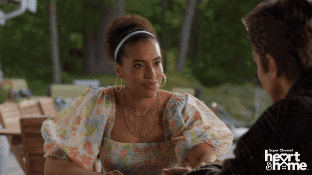 a woman in a floral dress sits at a table with a man in a plaid shirt and the words heart & me behind her