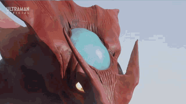 a red monster with a blue eye and the words ultraman official behind it