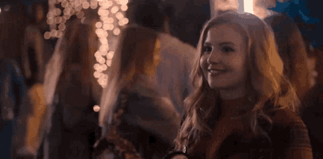 a woman is smiling while standing in a crowd of people .