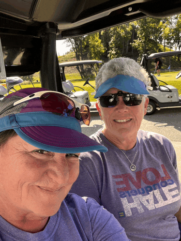 two women are sitting in a golf cart and one has a shirt that says " evolve "